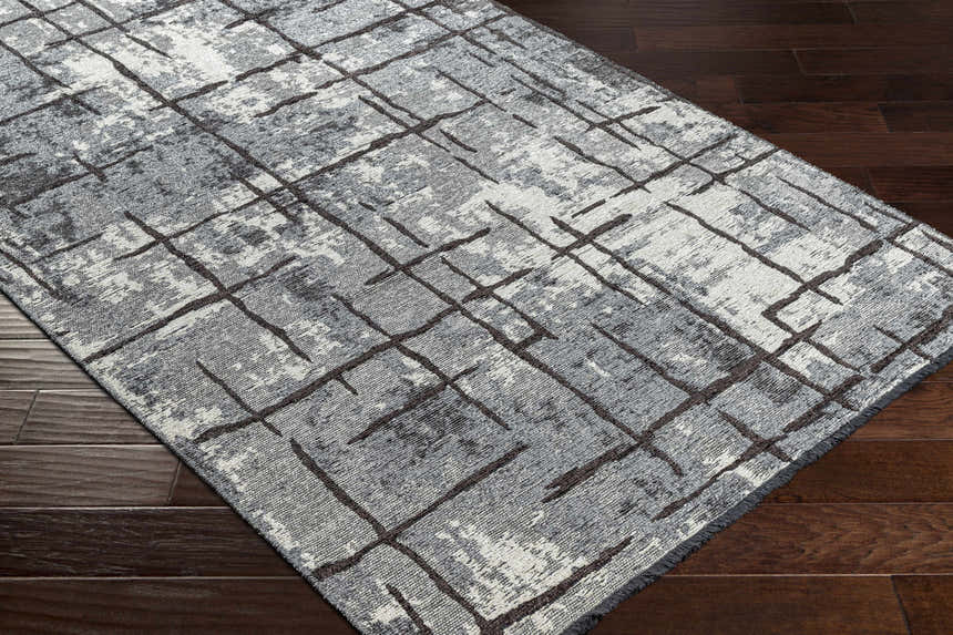 Close-up of Mace Area Rug: charcoal, cream, and slate geometric pattern on a chenille-polyester rug with a mid-century modern design. Corner