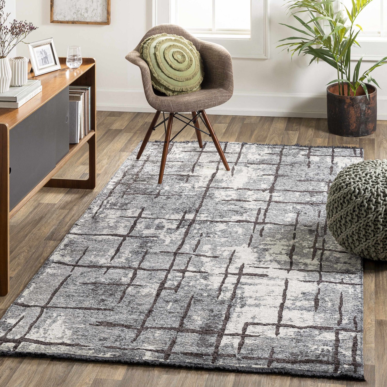 Living room scene with a charcoal and cream Mace Area Rug, wood furniture, chair, and green accents. Roomscene-Rectangle