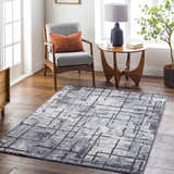 Living room scene with a charcoal and cream Mace Area Rug, gray chair, and mid-century modern decor. Roomscene-Rectangle
