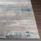 Close-up of the McCracken Area Rug: a contemporary design with blue, gray, white, and rust colors on dark wood floor. Front