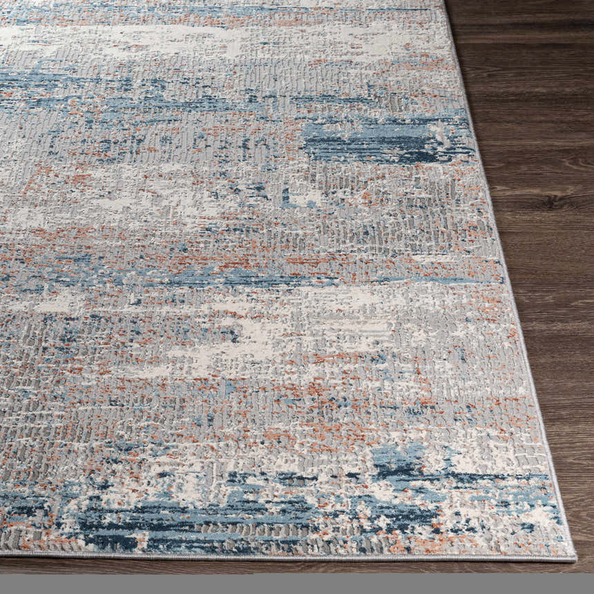 Close-up of the McCracken Area Rug: a contemporary design with blue, gray, white, and rust colors on dark wood floor. Front