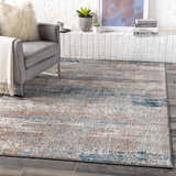 Living room scene with a gray chair and the McCracken Area Rug in blue and orange tones. Roomscene-Rectangle