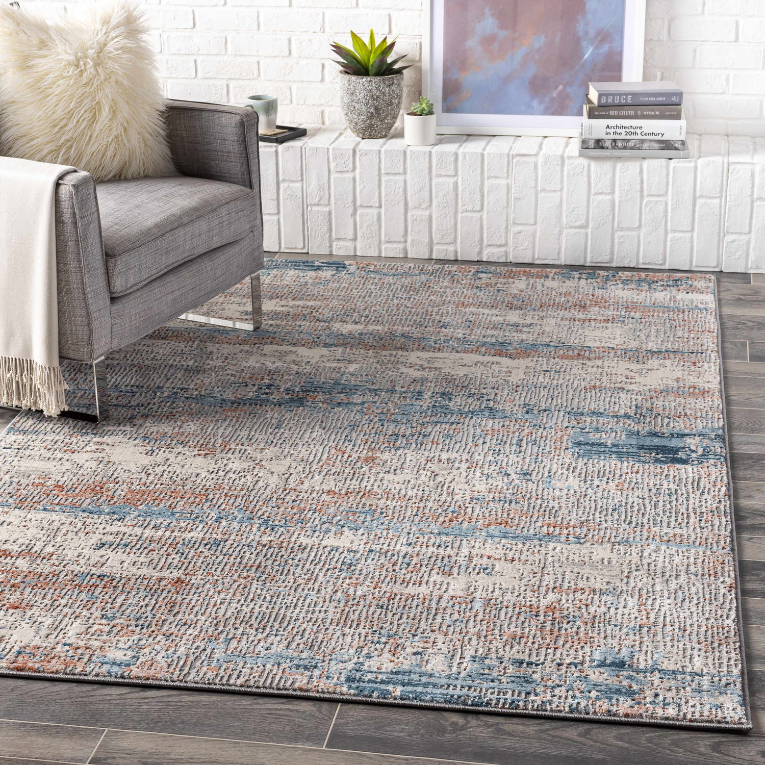 Living room scene with a gray chair and the McCracken Area Rug in blue and orange tones. Roomscene-Rectangle