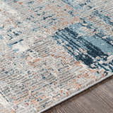 Close-up of the McCracken Area Rug showing its textured weave and abstract pattern in gray, blue, and coral. Texture