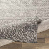 Close-up of the Mckinney Area Rug. Charcoal, light beige, and gray geometric pattern. Machine woven texture. Fold