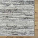 Close-up of the Munya Area Rug. Southwestern style rug in charcoal, cream, and gray on wood floor. Corner