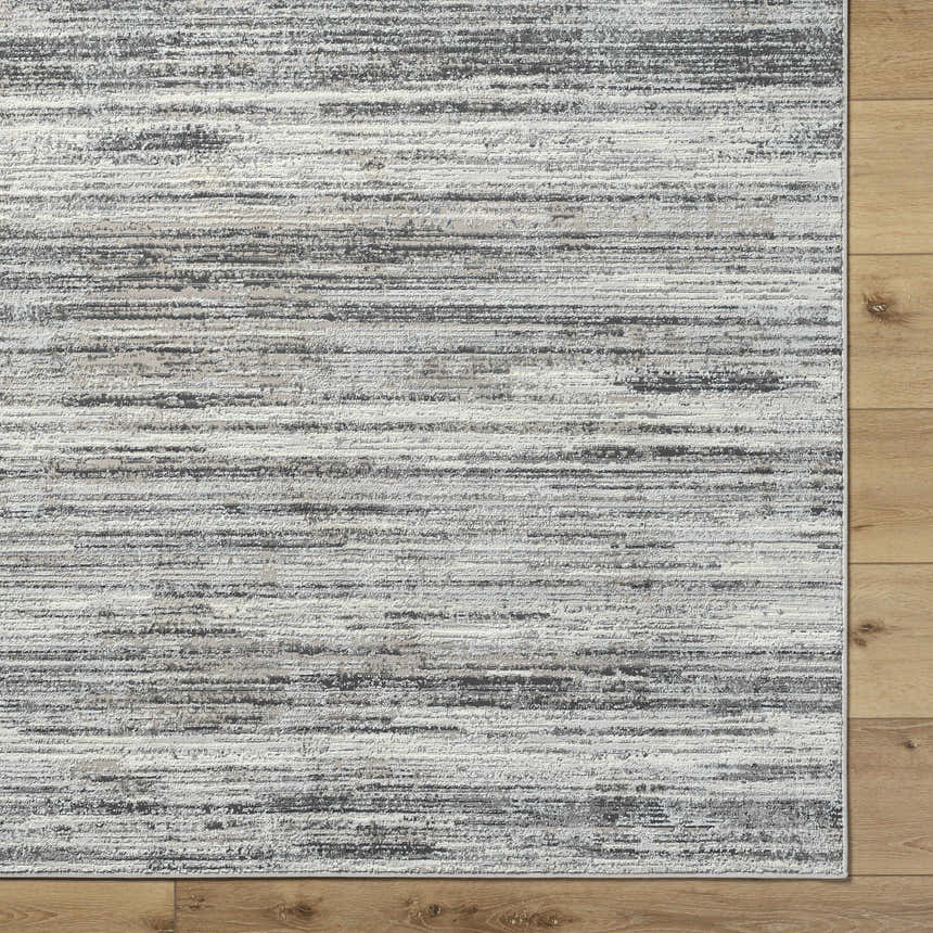Close-up of the Munya Area Rug. Southwestern style rug in charcoal, cream, and gray on wood floor. Corner