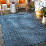 Blue Maddingley Flatweave Area Carpet on a patio with wicker chairs and orange pillows. Roomscene-Rectangle