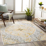 Living room scene with a Mehoopany Area Rug. Bohemian style rug in burnt orange, gray, and navy. Chair, plants, and light wood floors. Roomscene-Rectangle