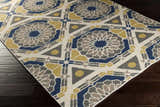 Close-up of the Mesena Area Rug featuring ivory, light gray, navy, and tan geometric patterns. Corner