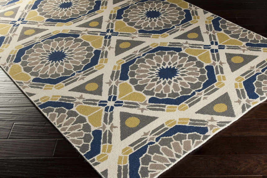 Close-up of the Mesena Area Rug featuring ivory, light gray, navy, and tan geometric patterns. Corner