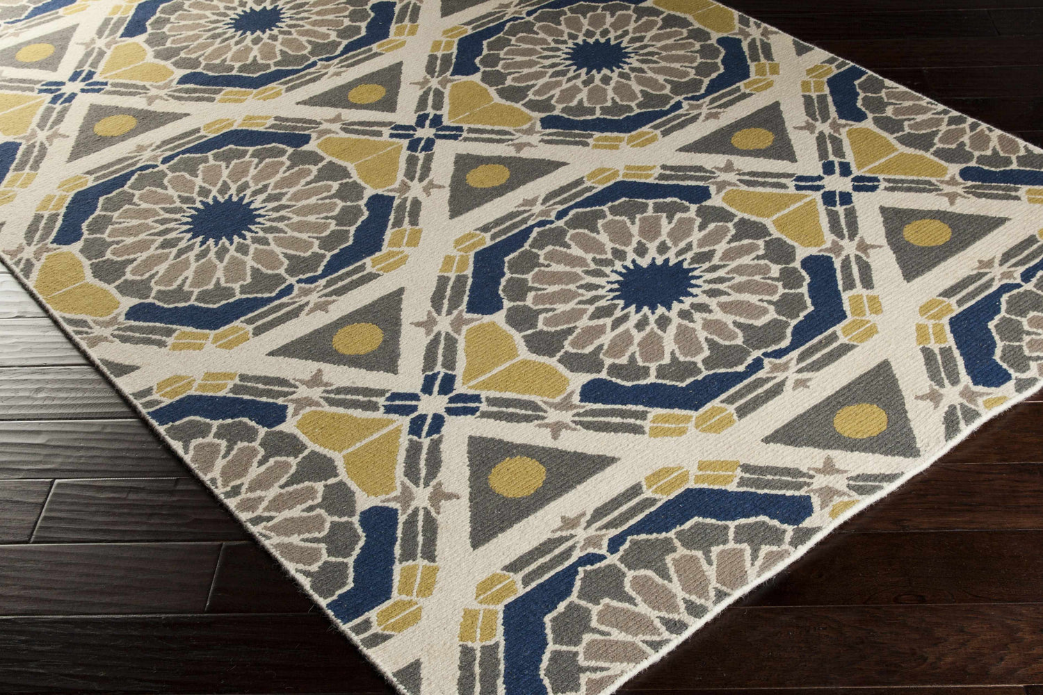 Close-up of the Mesena Area Rug featuring ivory, light gray, navy, and tan geometric patterns. Corner