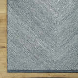 Close-up of a black and cream Wool Texture Area Rug. Hand-tufted rug with a contemporary herringbone pattern. Corner