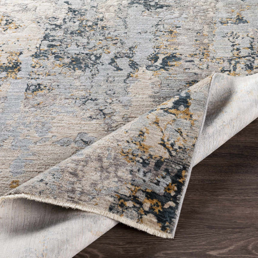 Close-up of the Midfield Luxe Rug showing its charcoal, cream, gray, and teal contemporary pattern and soft polyester texture. Fold