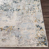 Close up of the Midfield Luxe Rug. Charcoal, cream, blue, and gray abstract pattern on a polyester rug with a short fringe. Front