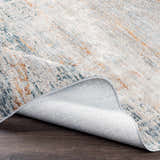 Close-up of the Midhurst Luxe Rug showing its cream, blue, and orange contemporary pattern and woven texture. Fold