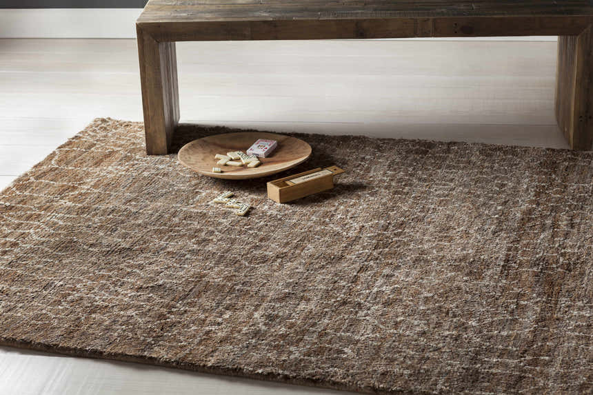 Close-up of the Milbridge Clearance Jute Rug in beige and brown, styled with a wood table and dominoes. Styleshot
