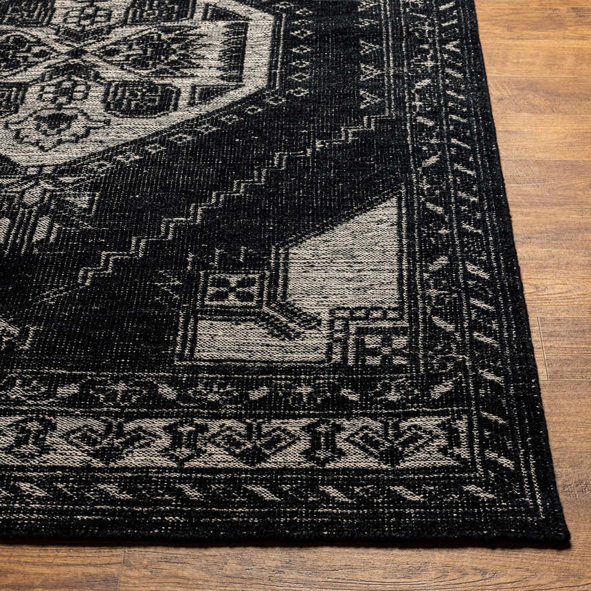 Close-up of the hand-knotted Minapan Premium Area Rug. Black and cream traditional oriental rug pattern on wood floor. Front