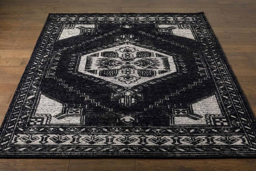Close-up of the Minapan Premium Area Rug. Black and cream traditional rug with an oriental pattern on a wood floor. Front