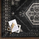 Close-up of the black and cream Minapan Premium Area Rug with a traditional oriental pattern and a cup of coffee on top. Styleshot