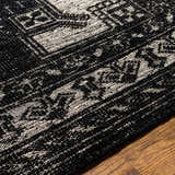 Close-up of the hand-knotted Minapan Premium Area Rug. Black and cream cotton and wool rug with traditional oriental pattern. Texture