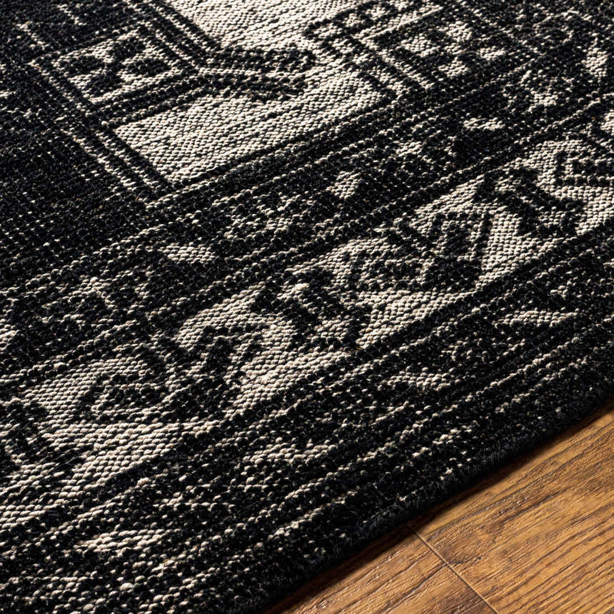 Close-up of the hand-knotted Minapan Premium Area Rug. Black and cream cotton and wool rug with traditional oriental pattern. Texture