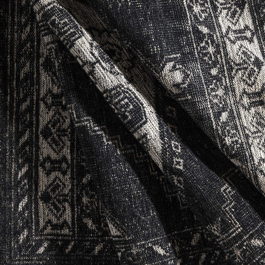 Close-up of the hand-knotted Minapan Premium Area Rug. Black and cream cotton and wool rug with a traditional oriental pattern. Fold