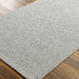 Close-up of the Medih Area Rug showing its gray woven texture and pattern on a wood floor. Corner