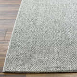 Close-up of the gray Medih Area Rug showing its woven texture and neutral color palette on a wood floor. Front