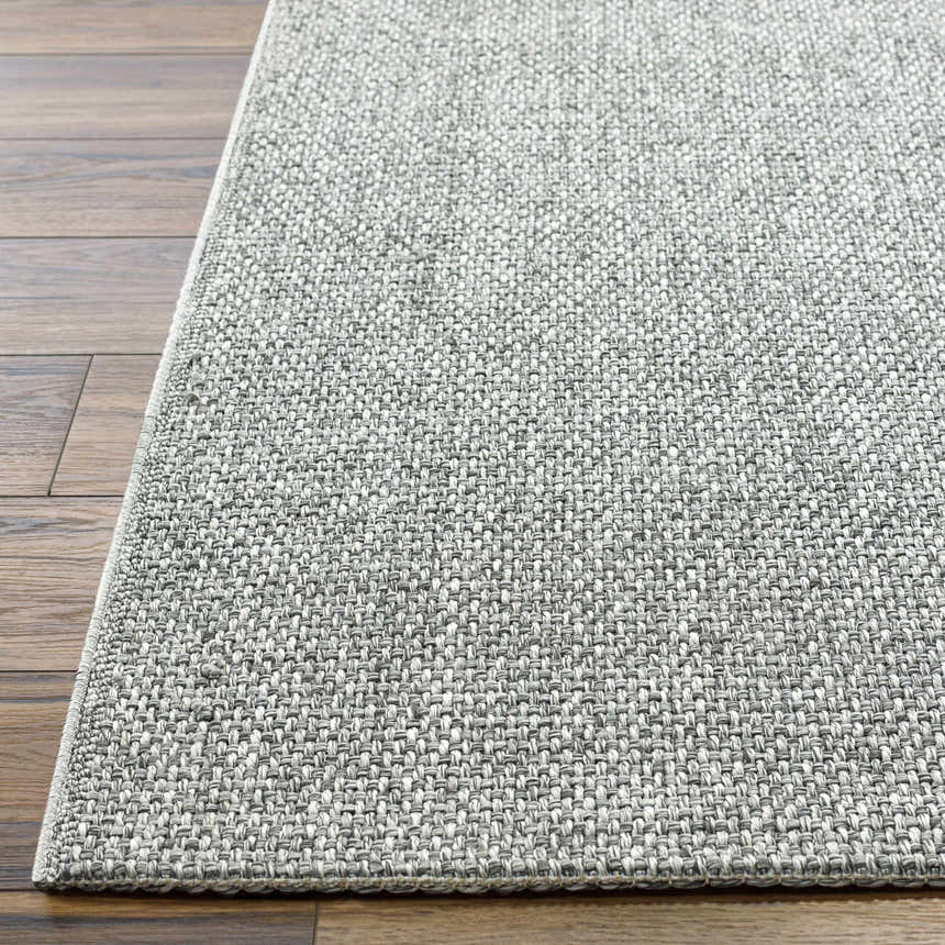 Close-up of the gray Medih Area Rug showing its woven texture and neutral color palette on a wood floor. Front