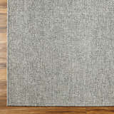 Close-up of the gray Medih Area Rug showing woven texture on wood floor. Polypropylene rug. Corner