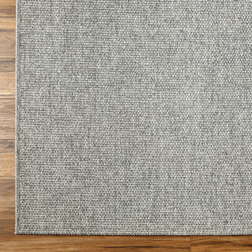 Close-up of the gray Medih Area Rug showing woven texture on wood floor. Polypropylene rug. Corner