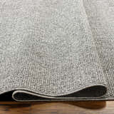 Close-up of the gray Medih Area Rug showing its woven texture and construction on a wood floor. Texture