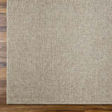 Close-up of the woven texture and pattern of the Matah Beige Outdoor Area Rug on dark wood flooring. Corner