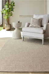 Outdoor patio scene with a Matah Beige Outdoor Area Rug, chair, side table, and potted plant. Roomscene-Rectangle