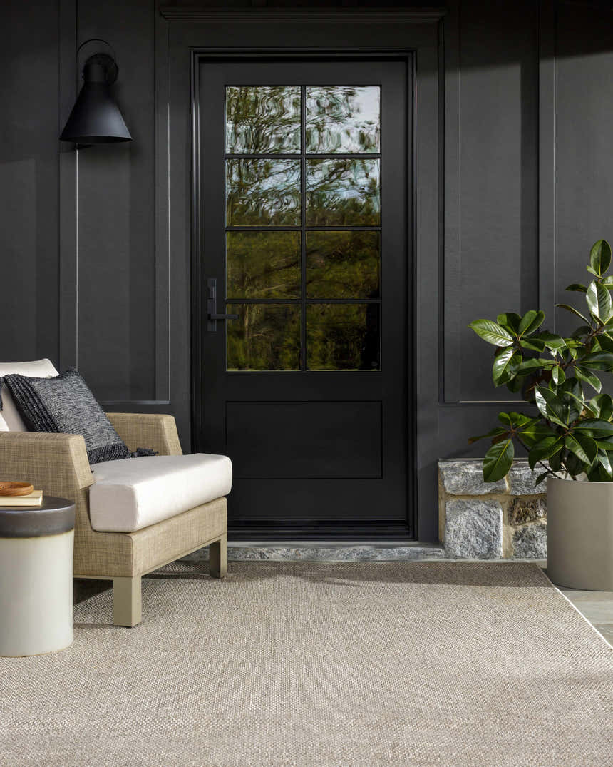 Outdoor patio scene with a Matah Beige Outdoor Area Rug, chair, and potted plant against a dark gray exterior. Roomscene-Rectangle