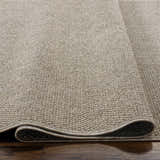 Close-up of the woven texture and rolled edge of the Matah Beige Outdoor Area Rug. Neutral tones. Texture