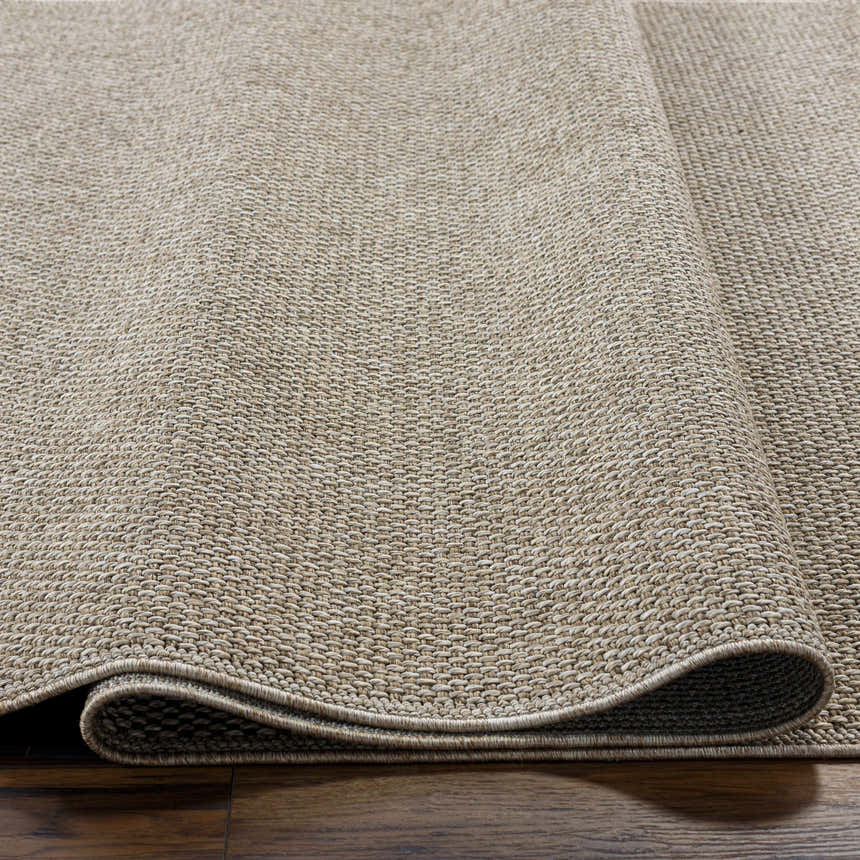 Close-up of the woven texture and rolled edge of the Matah Beige Outdoor Area Rug. Neutral tones. Texture