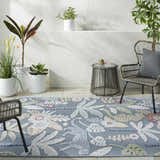 Indoor patio with blue Micha Area Rug, wicker chairs, side table, and potted plants. Floral and animal pattern. Roomscene-Rectangle