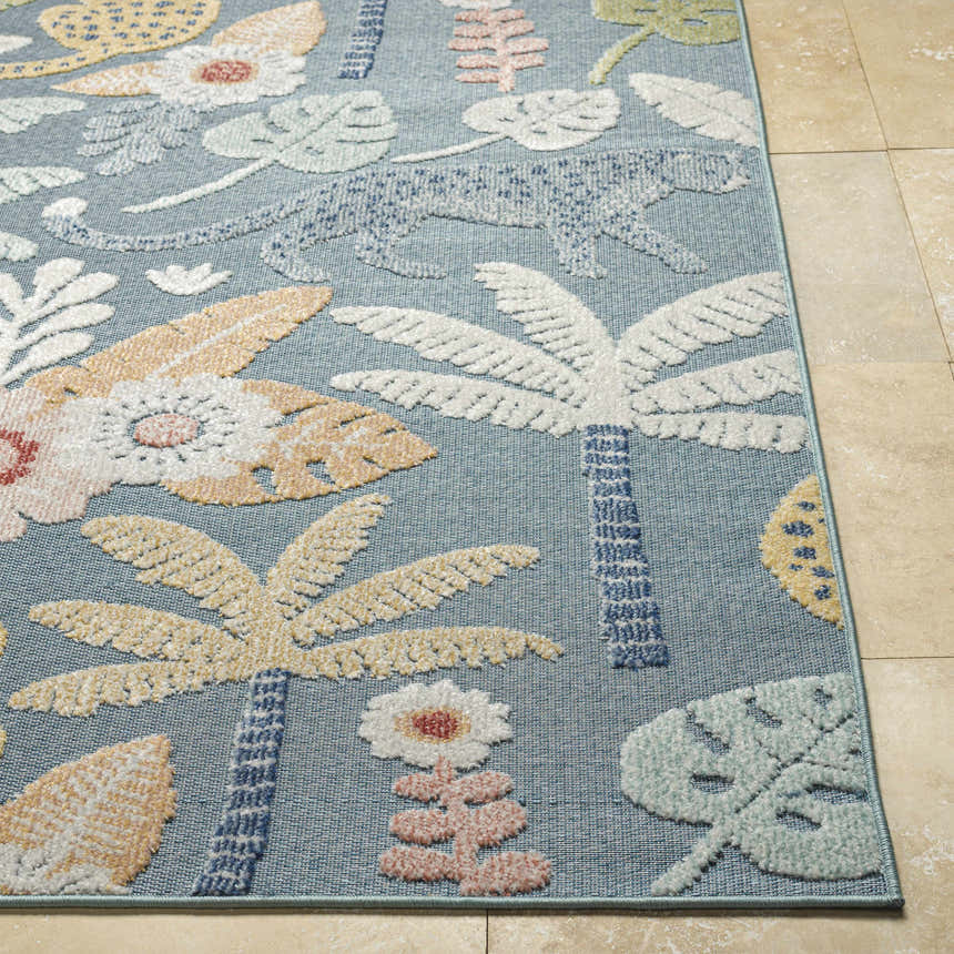 Close-up of the Micha Area Rug. Features a blue background with a floral and palm tree pattern in cream, mustard, and olive tones. Front