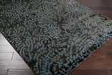 Close-up of the Pensacola Denim/Black rug showing its abstract denim blue pattern on a dark charcoal background. Corner