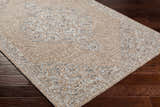 Close-up of the Modimolle Area Carpet showing its traditional Persian-style design in tan, cream, and gray on dark wood floors. Corner