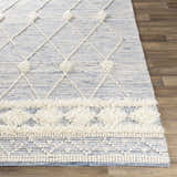 Close-up of the hand woven Moe Area Rug. Blue and cream rug with diamond pattern and textured wool accents. Front