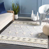Coastal living room scene with a blue and cream Moe Area Rug, sofa, and white chair. Roomscene-Rectangle