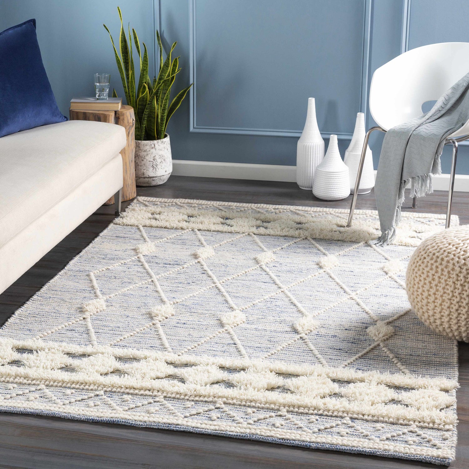 Coastal living room scene with a blue and cream Moe Area Rug, sofa, and white chair. Roomscene-Rectangle