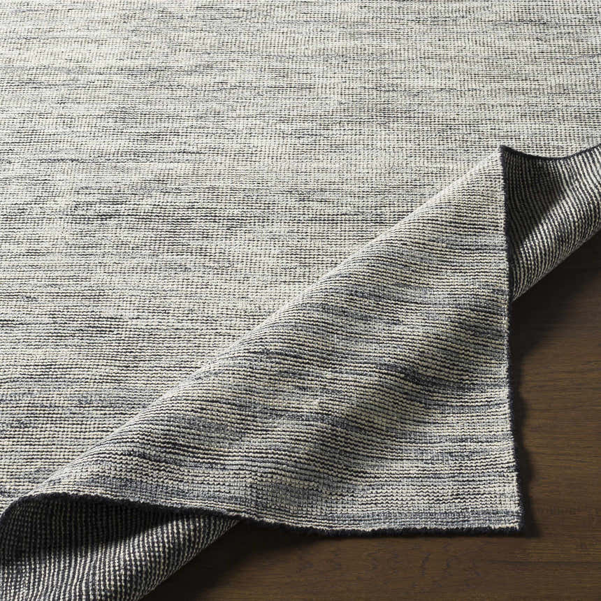 Close-up of the hand-knotted Molena Area Rug. Denim, ink blue, light olive, and light sage wool rug with a contemporary design. Front