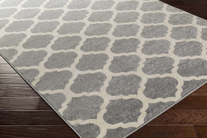 Close-up of the Mongo Carpet, a cream and slate rug with a contemporary geometric pattern on dark wood flooring. Corner