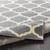 Close-up of the Mongo Carpet in cream and slate, featuring a contemporary quatrefoil pattern and machine-woven texture. Fold