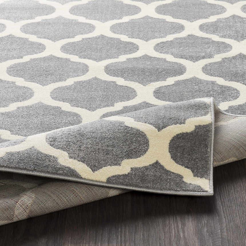 Close-up of the Mongo Carpet in cream and slate, featuring a contemporary quatrefoil pattern and machine-woven texture. Fold