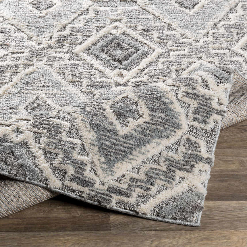 Close-up of the Moruya Area Rug showing its geometric pattern, beige, charcoal, cream and gray colors, and soft texture. Fold